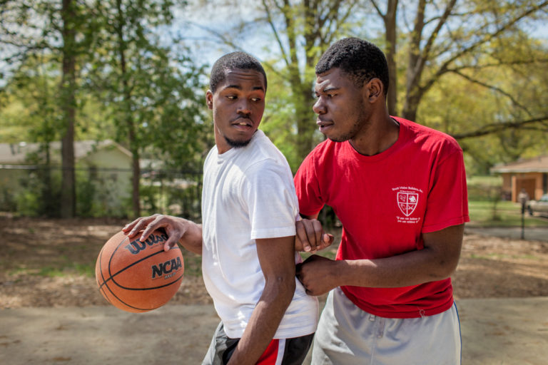 Rickey and brother, Reginald, play basketball on the court behind their home.